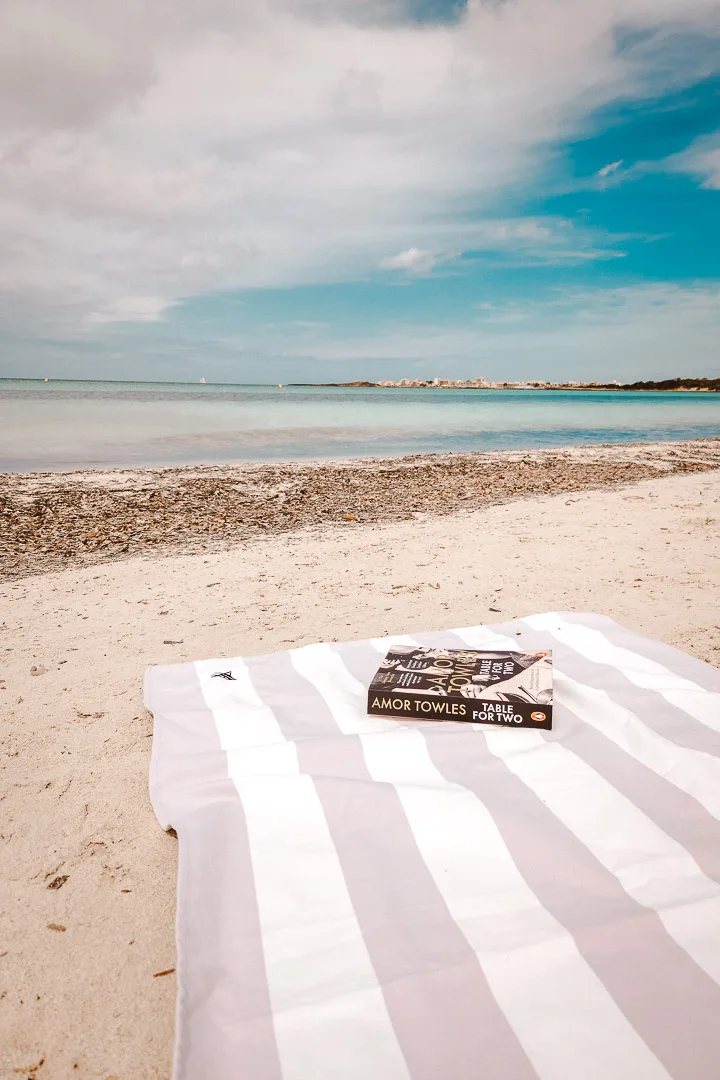 platja es carbo each towel with book on it in front of the sea