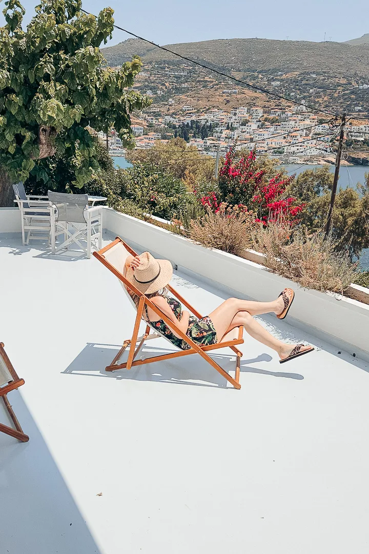 woman on deckchair on terrace looking out at Batsi village and sea