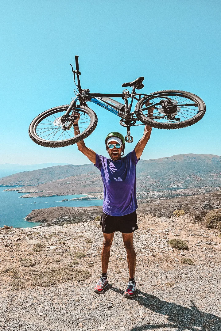 man holding up an ebike with chora coast behind him
