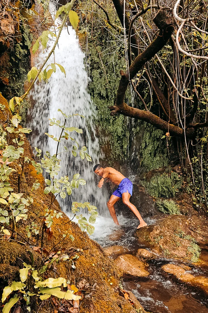 man getting head wet under waterfall