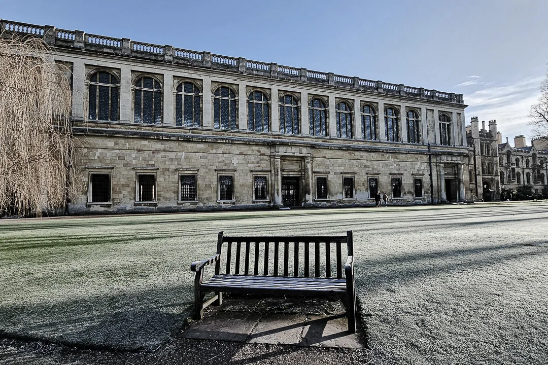 Cambridge bench outside of the Wren library in winter with frost on the ground