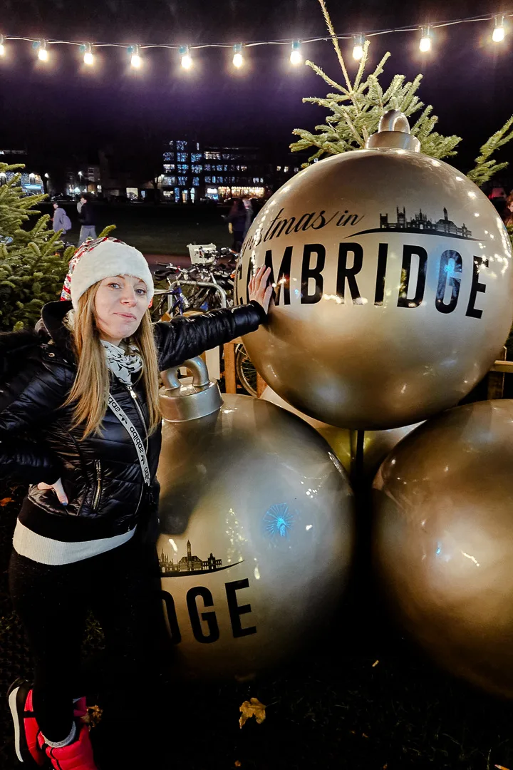 woman with giant Christmas baubles at cambridge Christmas market