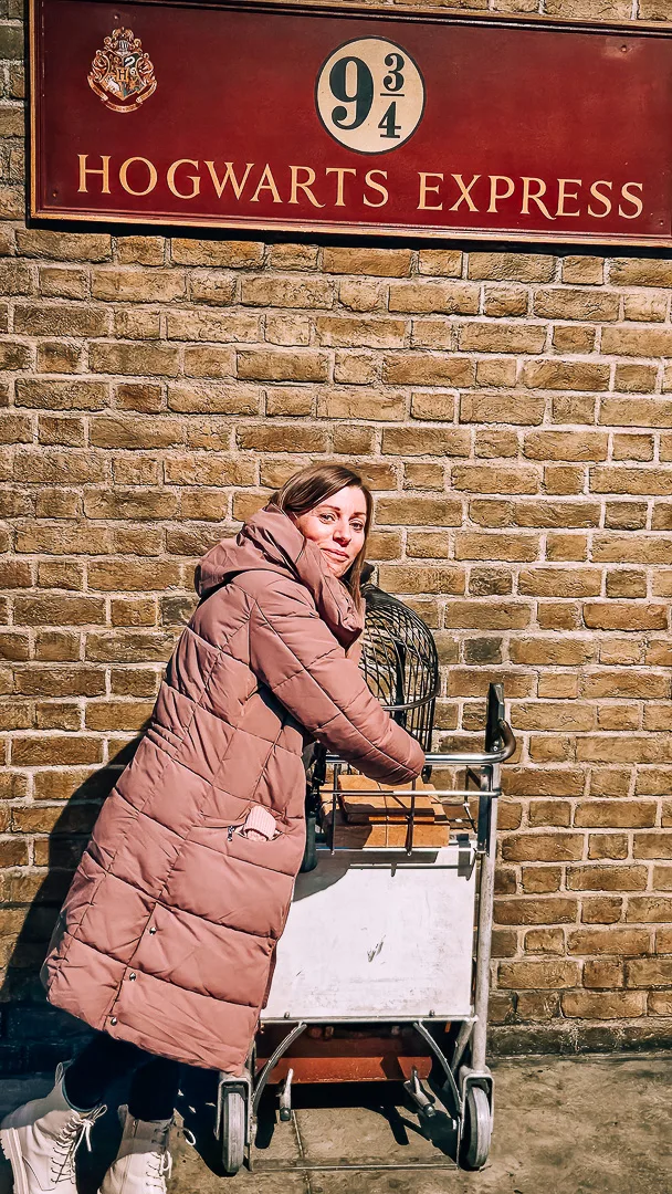 hogwarts express sign with lady pushing trolley through wall
